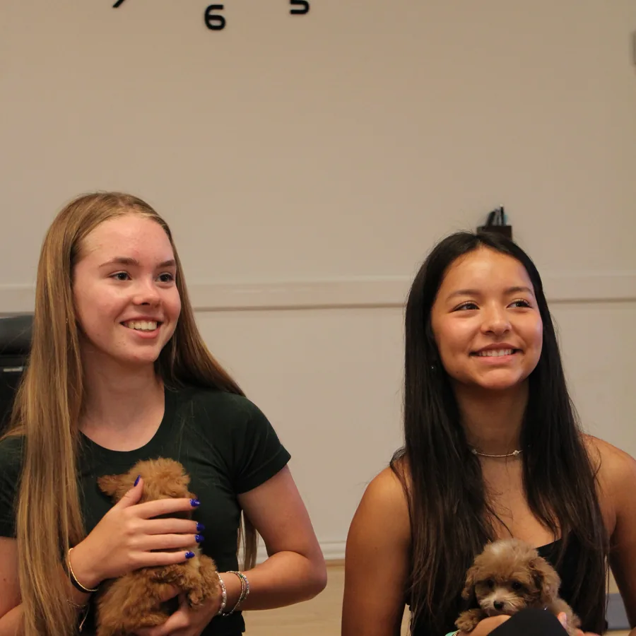Two guests smiling with their puppies at Pawty Yoga Houston's June 27 grand opening