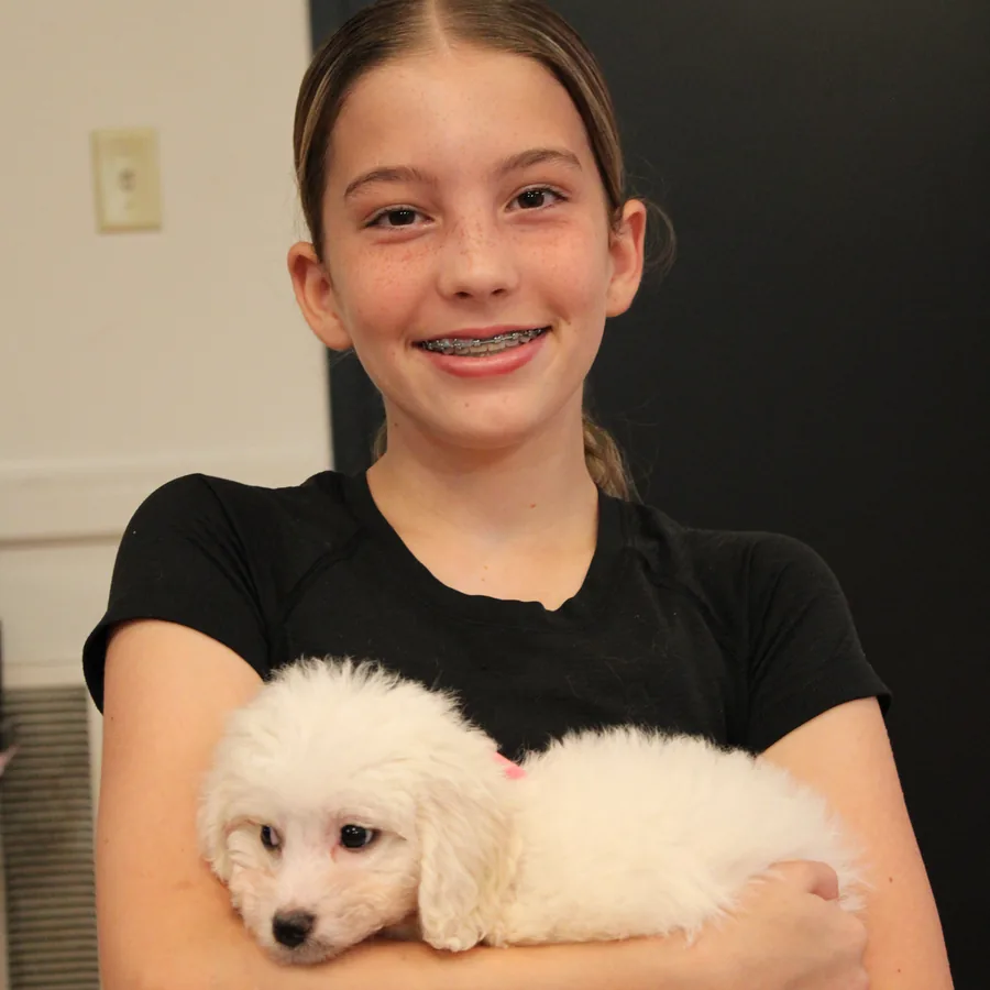 Young guest holding a white puppy at Pawty Yoga Houston