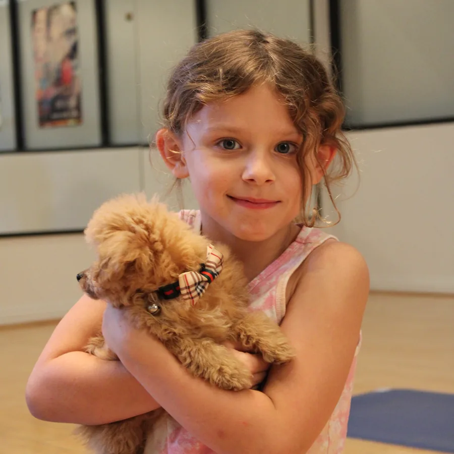 Young guest cuddling an apricot puppy at Pawty Yoga Houston