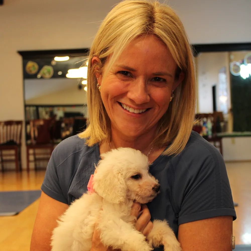 Guest smiling with a cream puppy at Pawty Yoga Houston, August 8 and 9 sessions