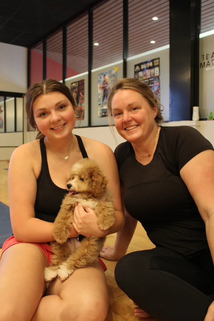 Friends holding an apricot puppy at Pawty Yoga Houston's June 27 grand opening