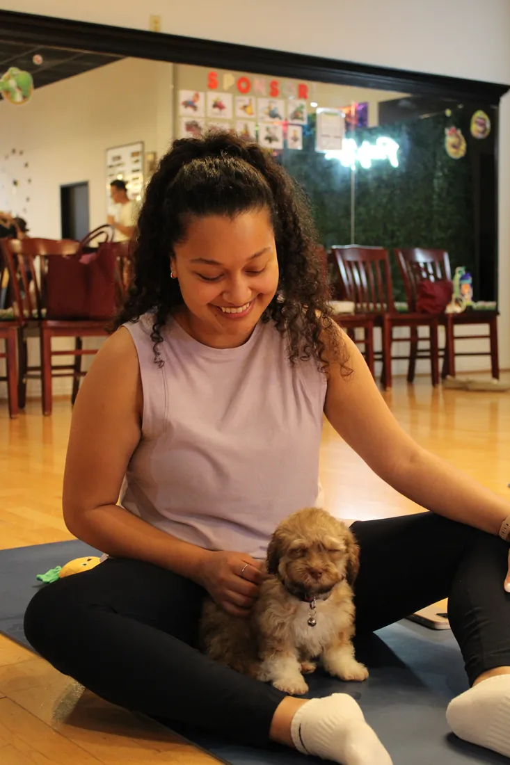 Guest relaxing with a puppy on the mat at a Houston puppy yoga class