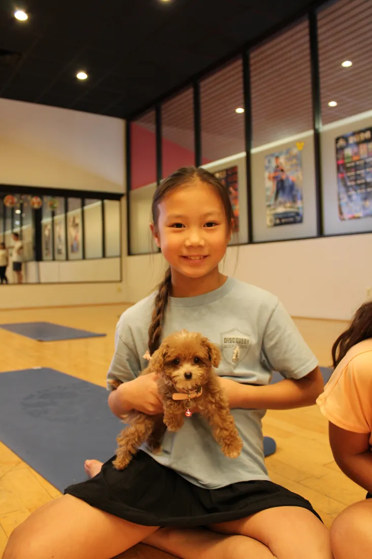 A child laughing with a puppy at a Pawty Yoga birthday event in Houston
