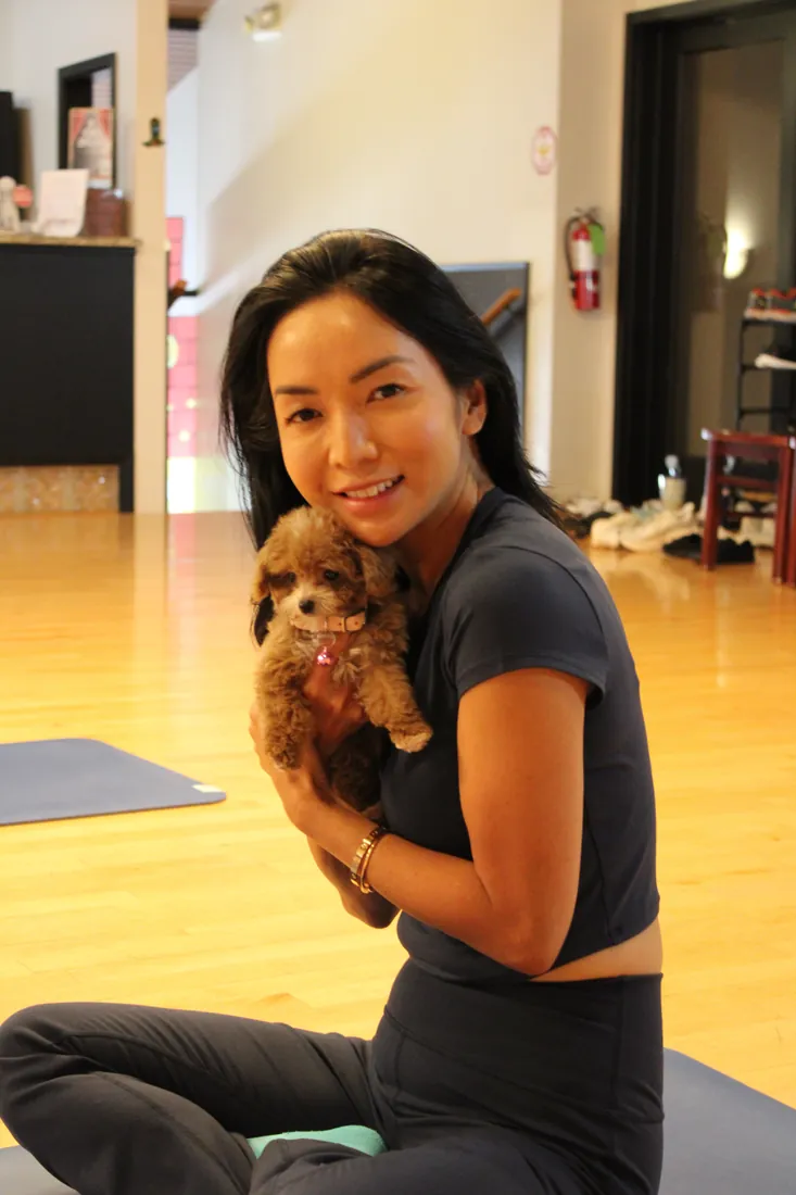 Guest smiling with a puppy in the Pawty Yoga Houston studio