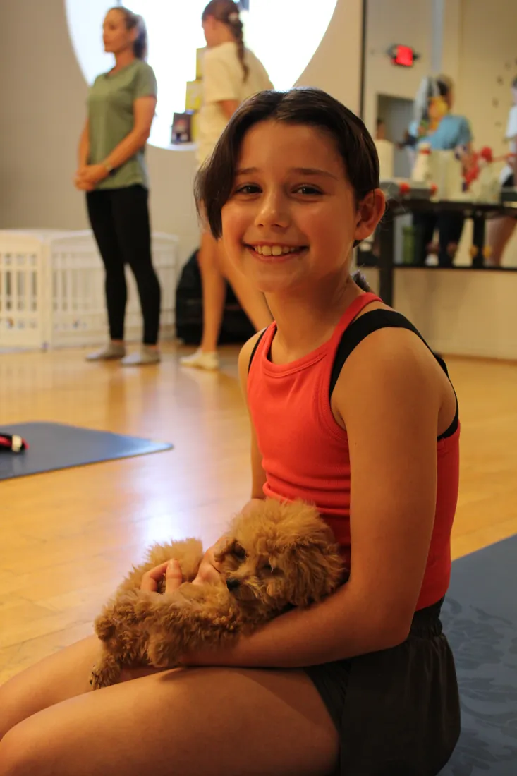 Young guest holding an apricot puppy at Pawty Yoga Houston