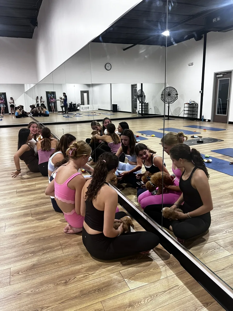 Guests sitting in a circle with puppies at a private Pawty Yoga event in Houston