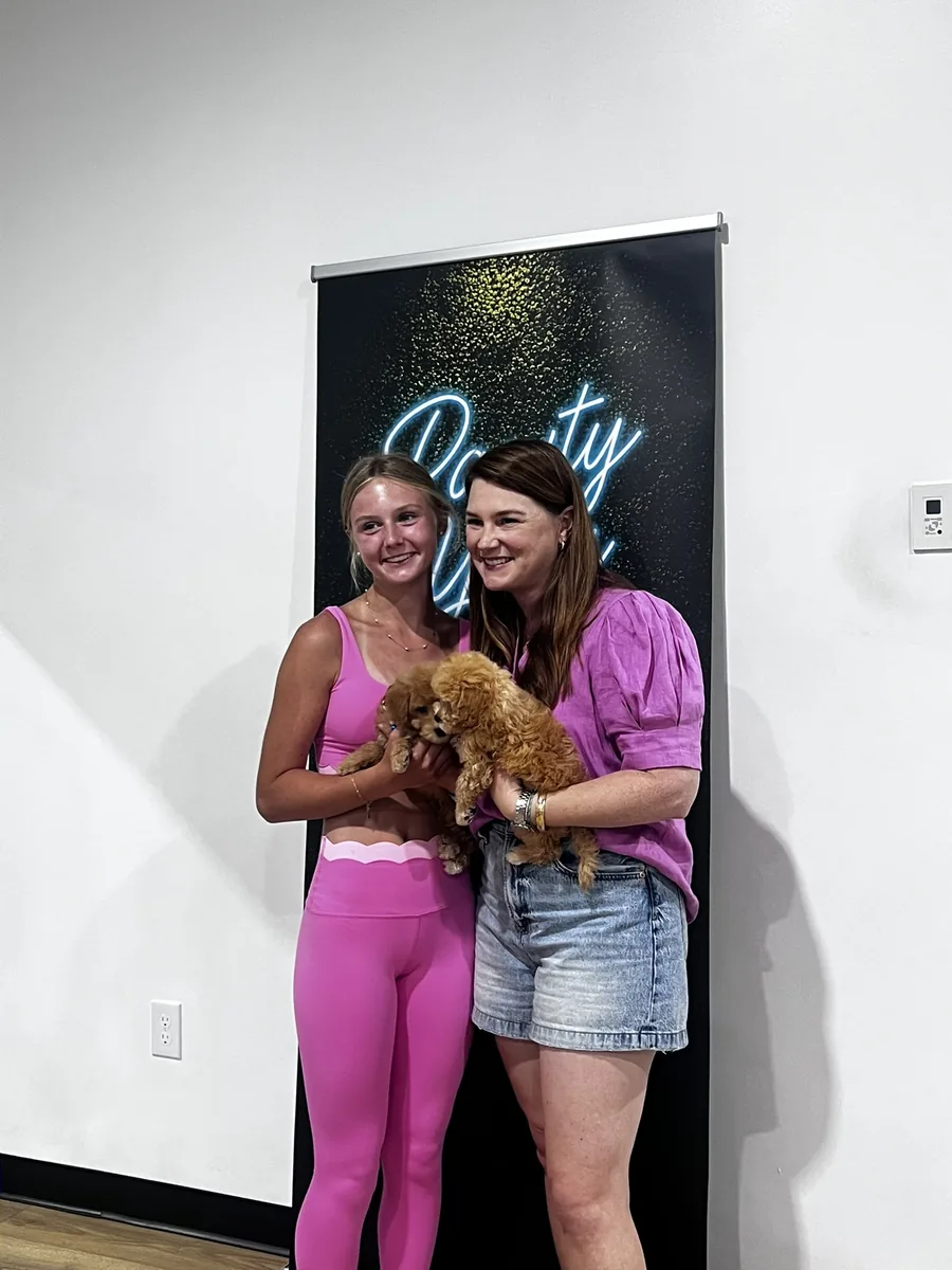 Two guests holding a puppy at a private Houston puppy yoga party
