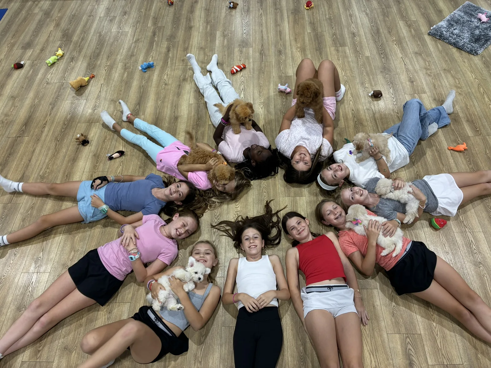 Kids lying in a star shape with puppies at a Houston Halloween puppy yoga party