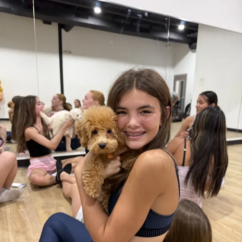 A teen cuddling a fluffy puppy at a Houston puppy yoga class