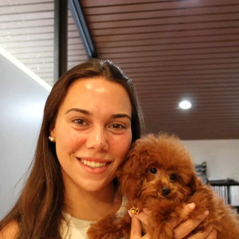 A woman holding a red poodle puppy cheek to cheek at Houston puppy yoga