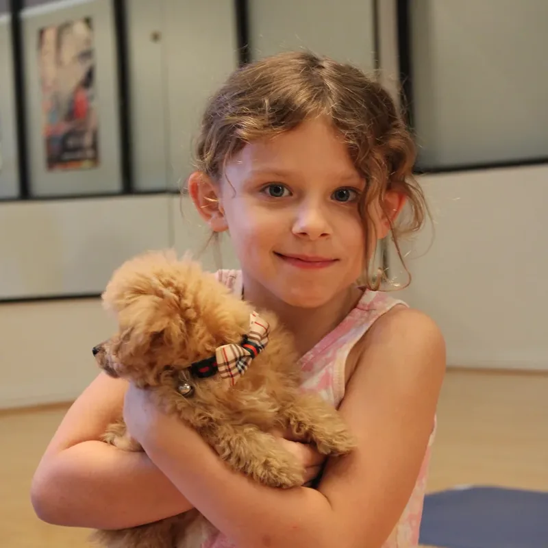 A young girl hugging a fluffy puppy at Houston puppy yoga