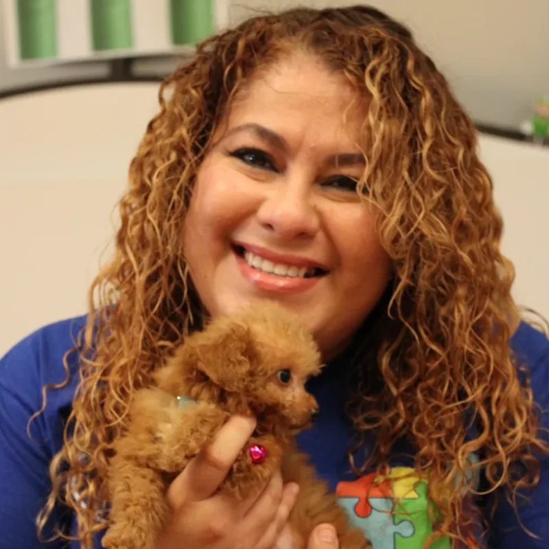 A smiling woman holding a puppy at a Houston puppy yoga class