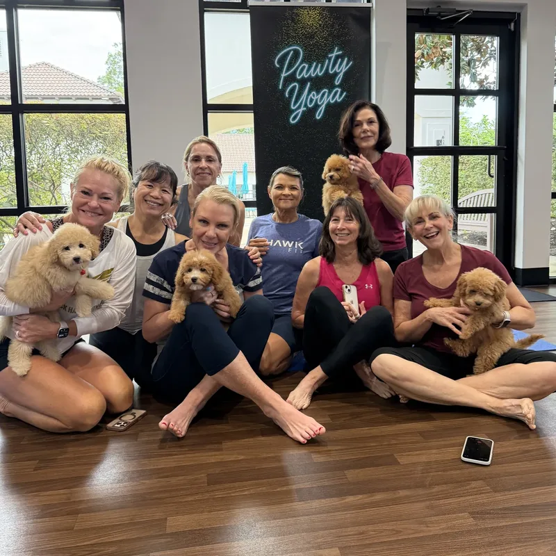 A group of adults smiling with puppies after a Houston puppy yoga class