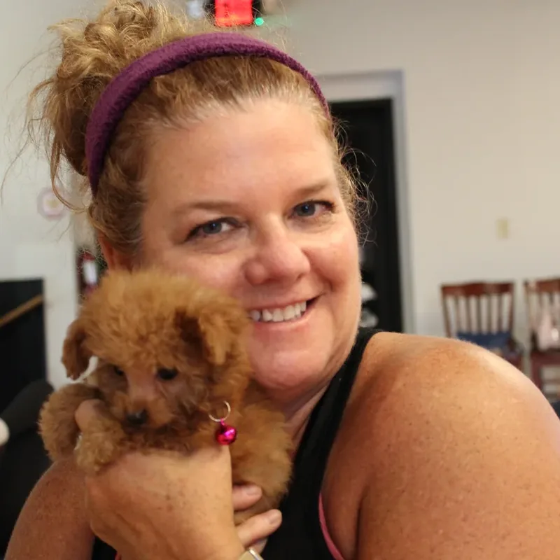 A woman cuddling a red puppy close at a Houston puppy yoga class